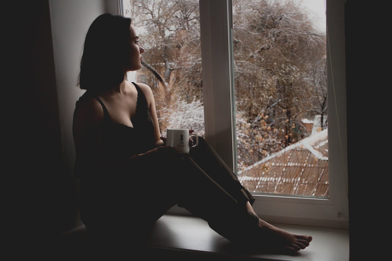 Sad woman sitting on a window ledge