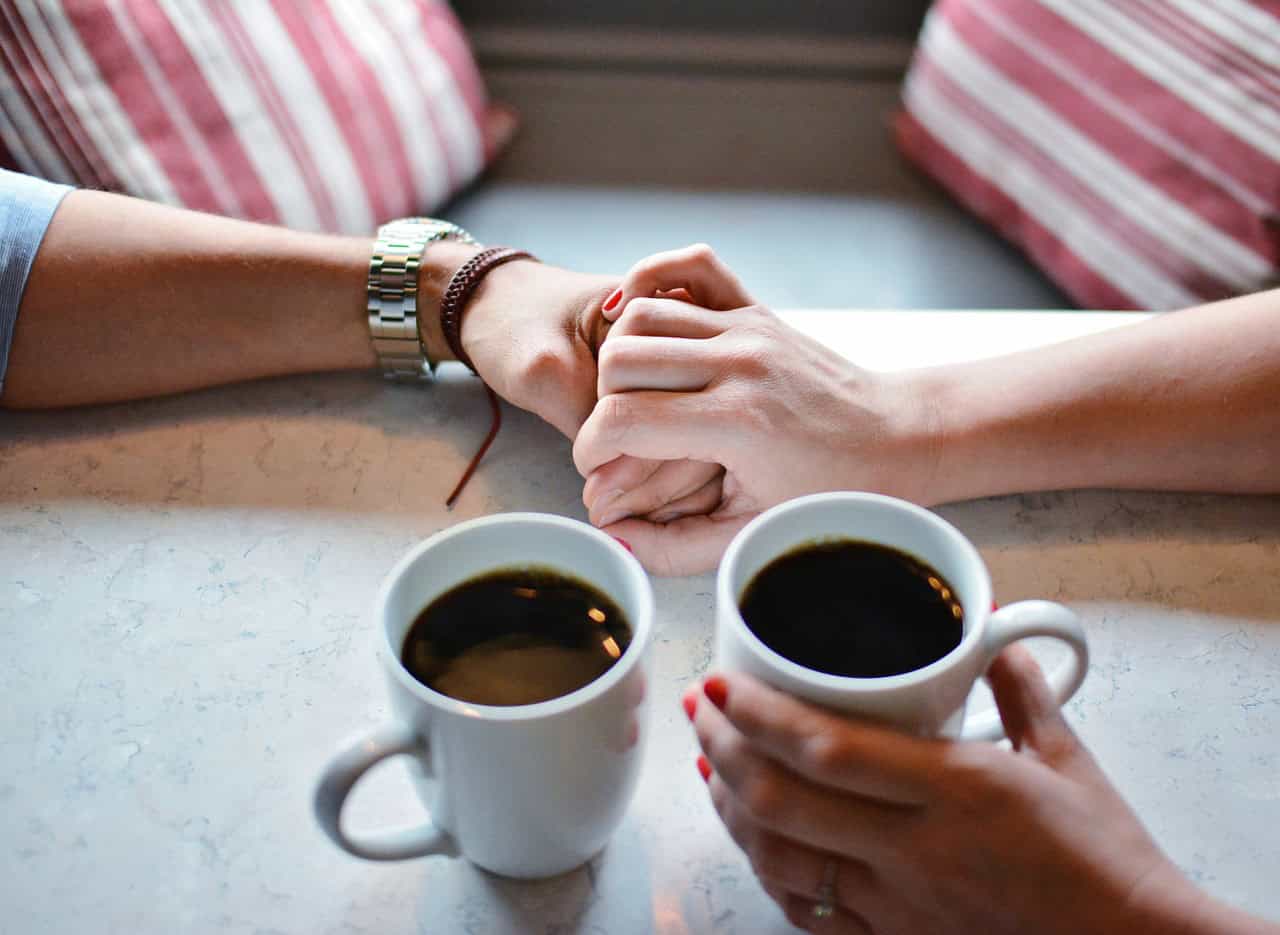 two people holding hands drinking coffee